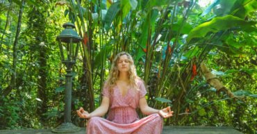 woman in pink dress sitting on wooden pathway